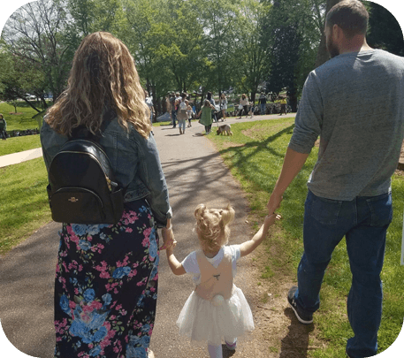 A woman and man holding hands with a little girl.