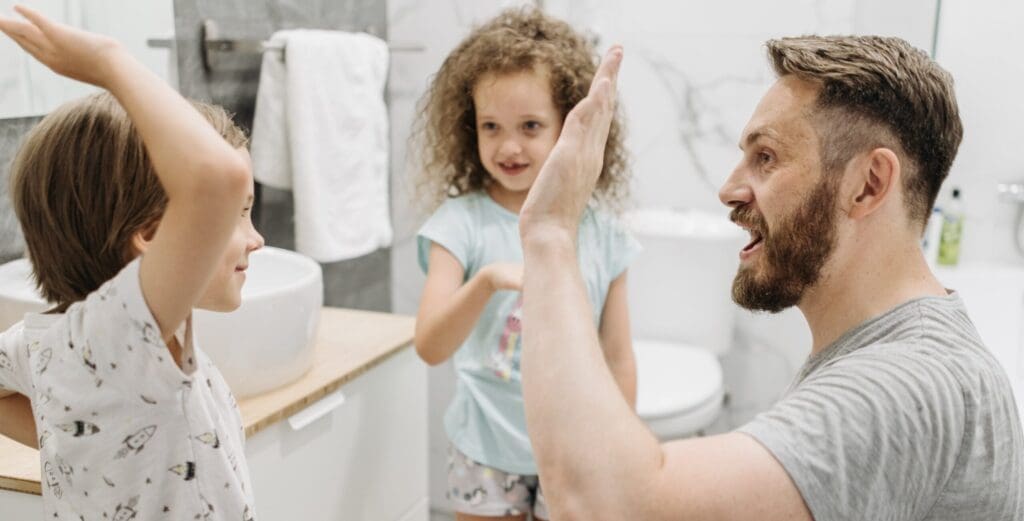 A man and girl in the bathroom with one hand up to his face.