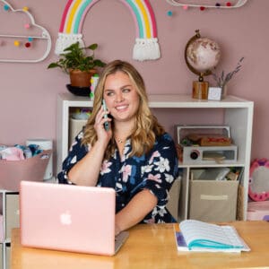 A woman sitting at a desk with a laptop and phone.