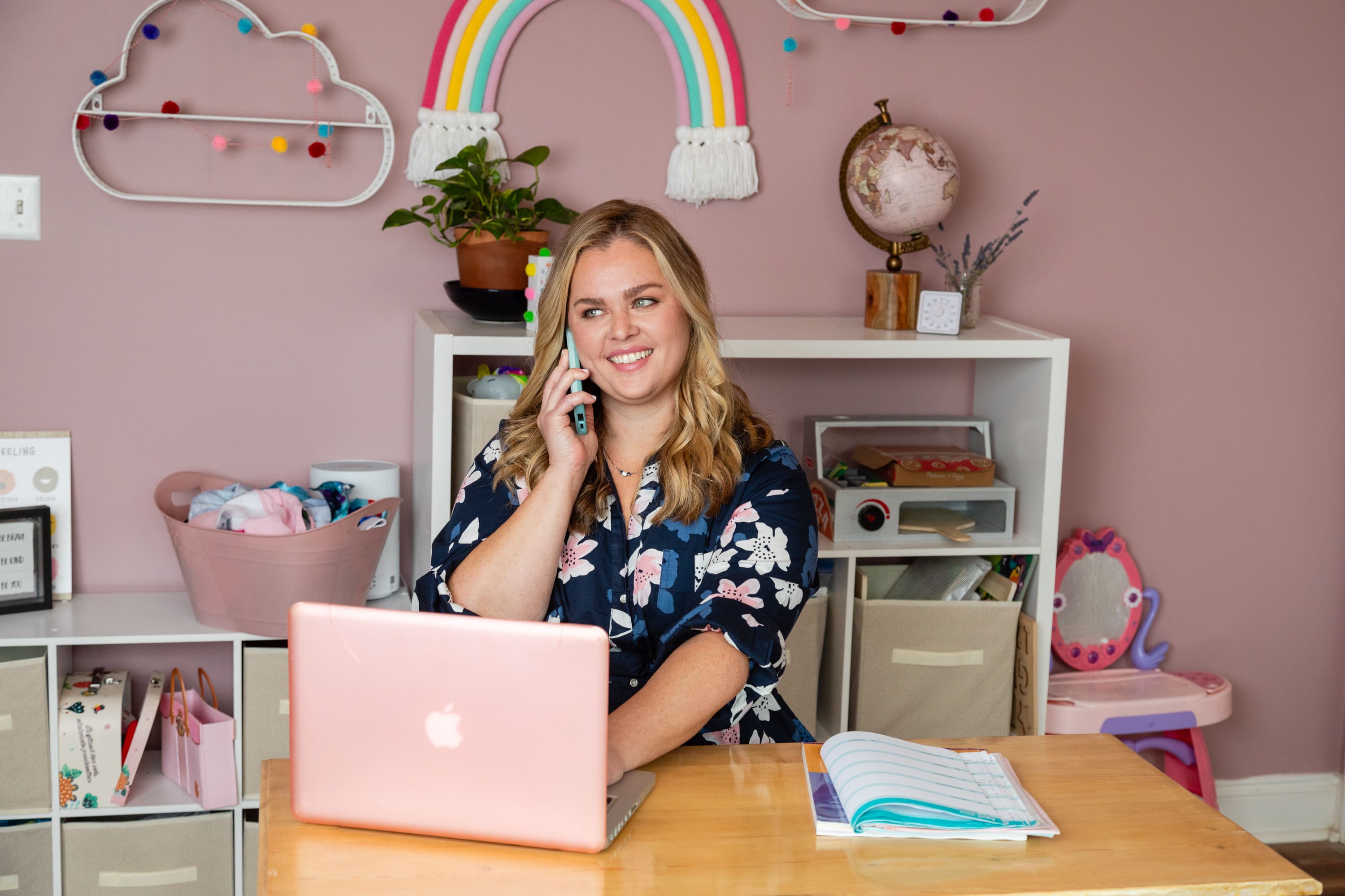 A woman sitting at a desk with a laptop and phone.