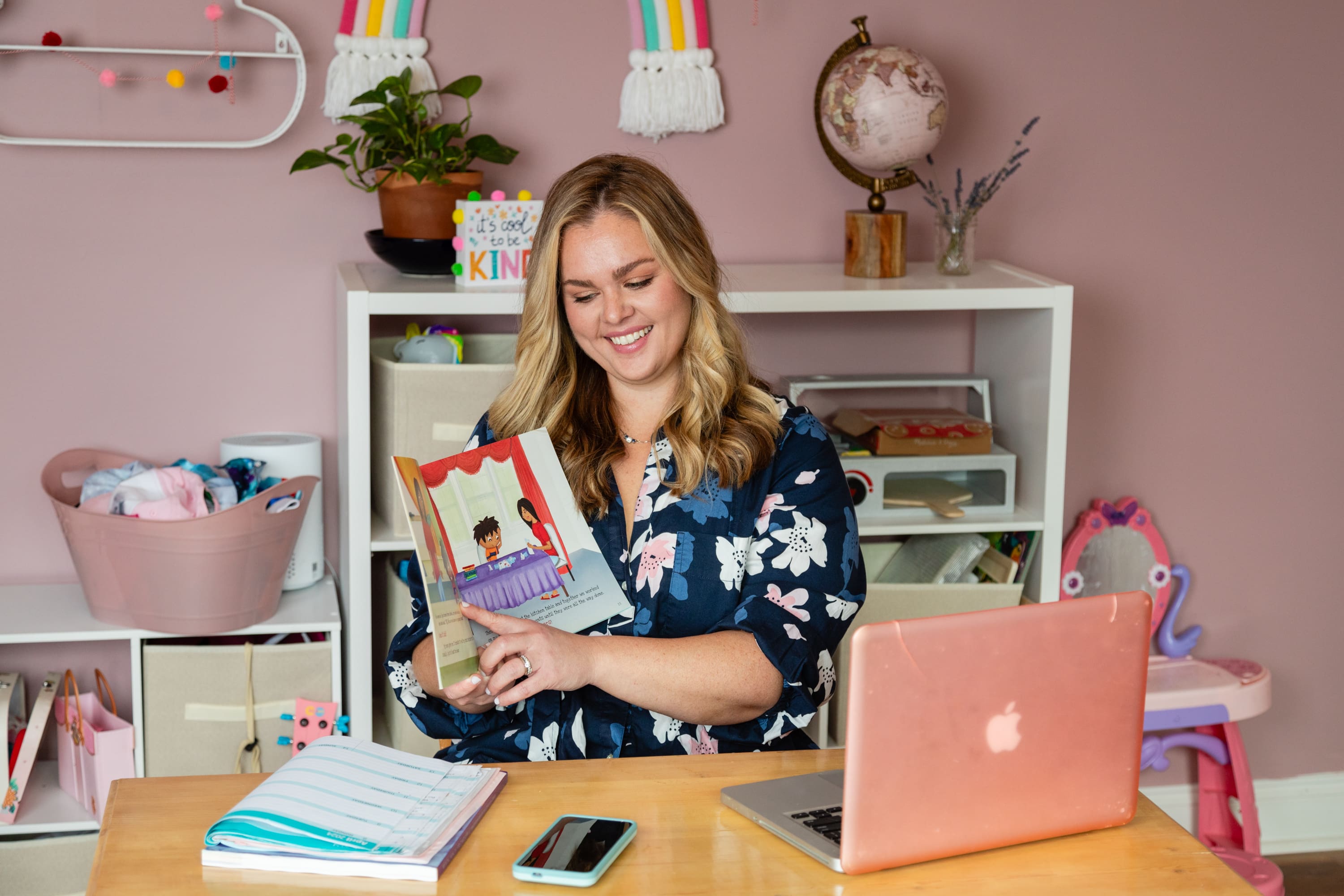 A woman sitting at her desk holding an open book.