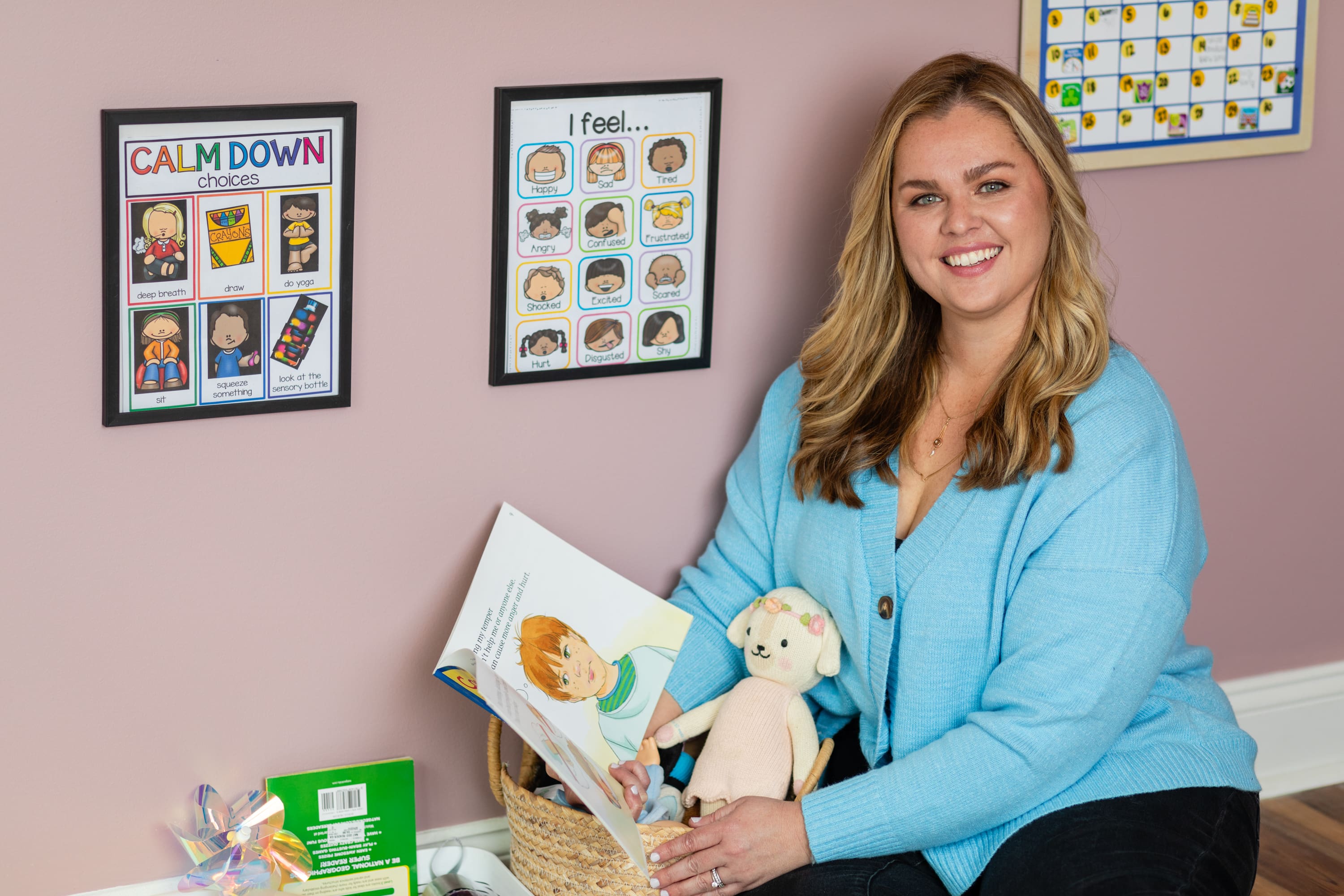 A woman sitting in front of some pictures holding a teddy bear.